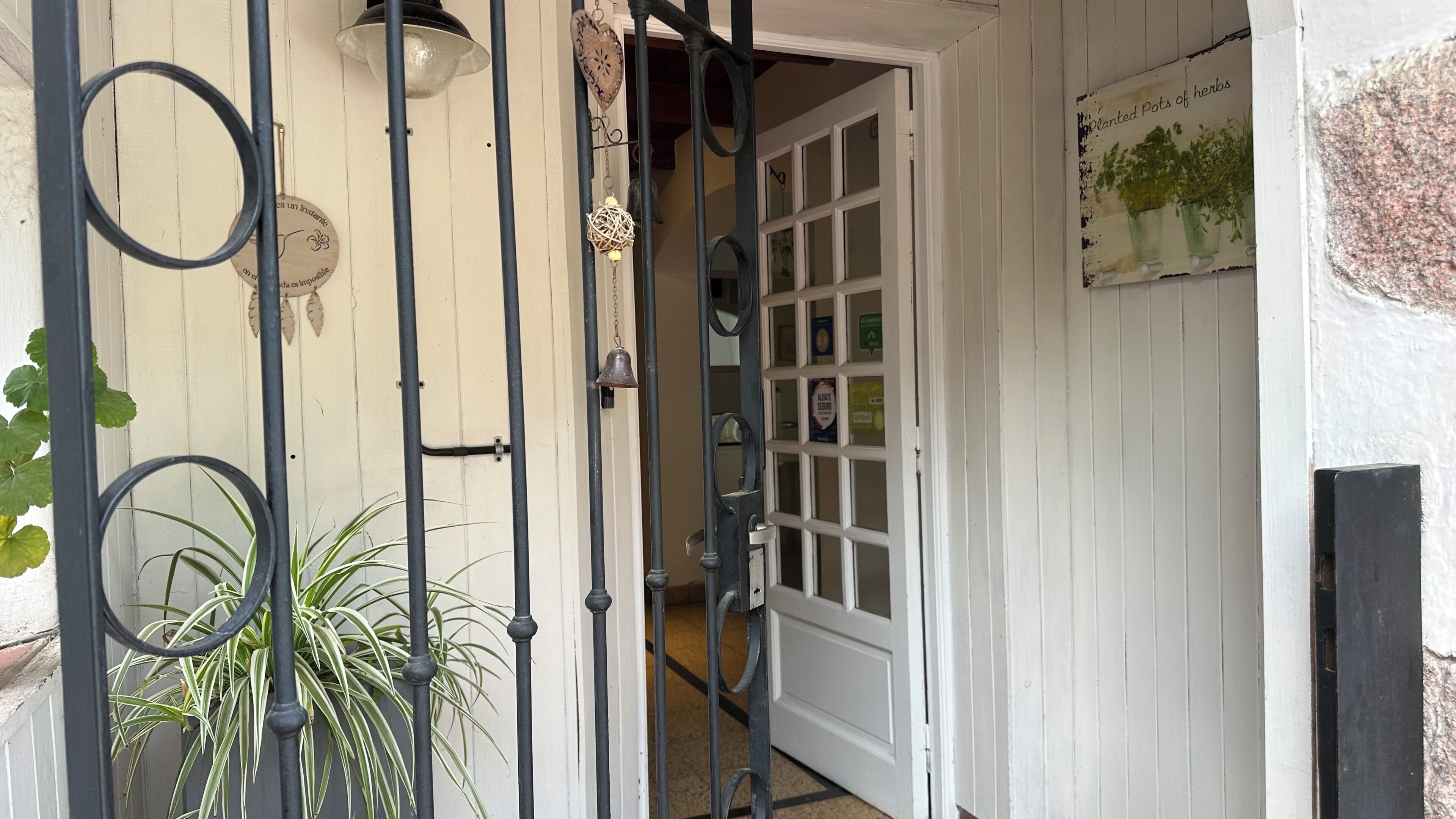 A white door with a glass panel, a metal gate with circular designs, and a sign with a plant illustration.