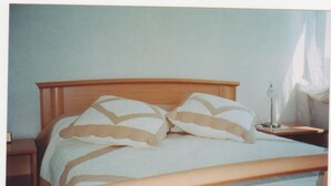 A bed with a wooden headboard, two pillows, a bedside table with a lamp, and a nightstand.