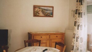A dining area with a table, chairs, a cabinet, and a painting on the wall.
