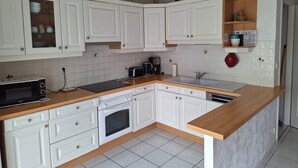A modern kitchen with white cabinets, a wooden countertop, a built-in oven, and a coffee maker.
