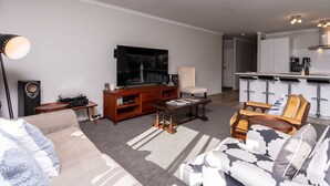 Moderni olohuone, jossa on sohva, sohvapöytä, televisio ja keittiöalue, jossa on baaritiski.