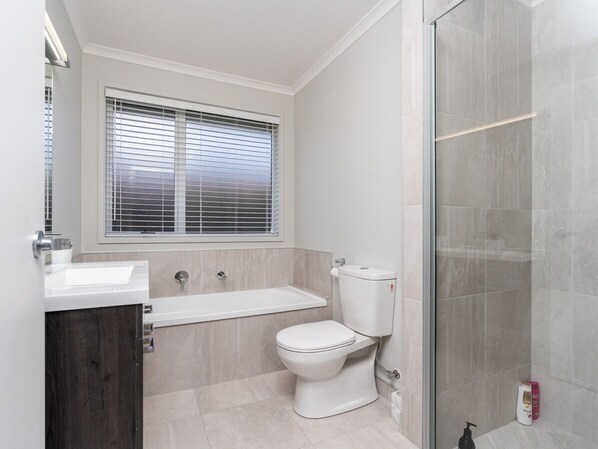 Et stilfuldt badeværelse med toilet, badekar og bruser.