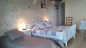 A bedroom with a bed, bedside table, lamp, and a chair. - Domaine de la Rue (La Berthenoux)