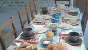 A breakfast table set with bread, pastries, and a fruit bowl. - Domaine de la Rue (La Berthenoux)