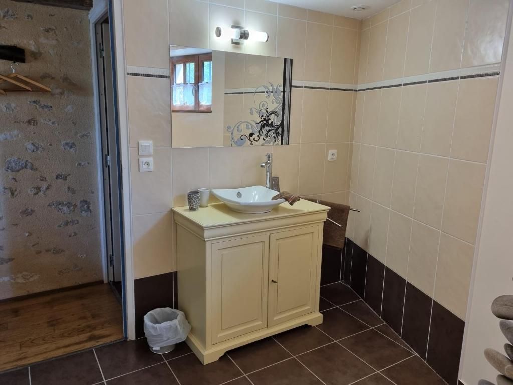 Un baño con lavamanos, espejo y mueble de almacenamiento.
