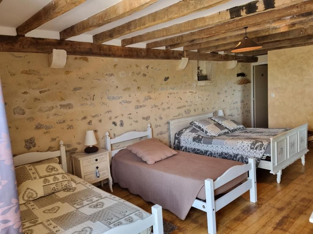 Une chambre avec deux lits, des poutres en bois au plafond et un mur décoré de motifs.