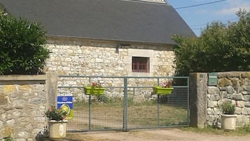 Een gebouw van steen met een metalen hek, plantenbakken en een bord dat een restaurant aangeeft.