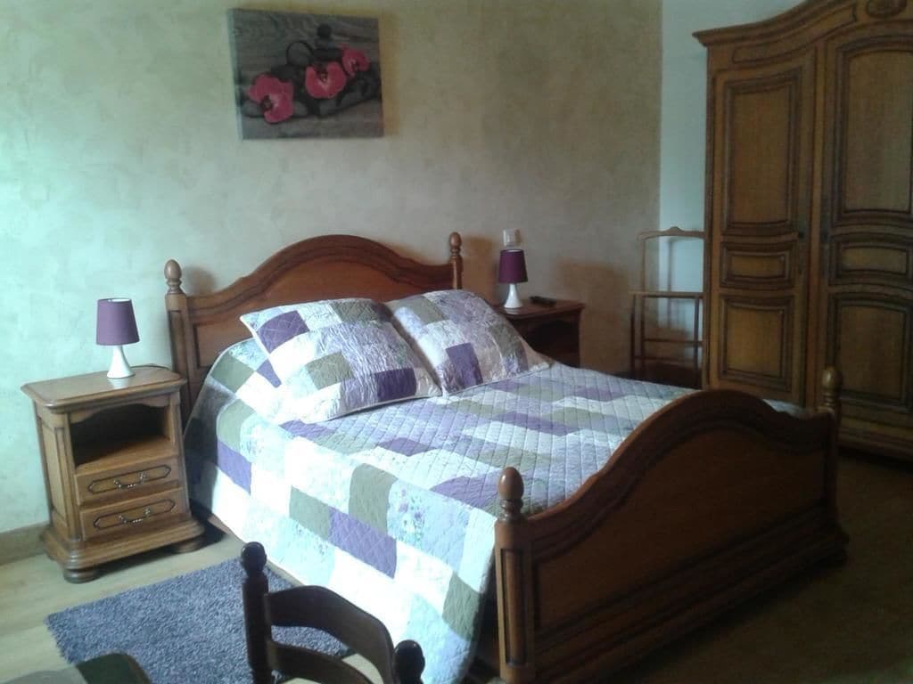 A bedroom with a wooden bed, two bedside tables, a nightstand, a dresser, and a painting on the wall.