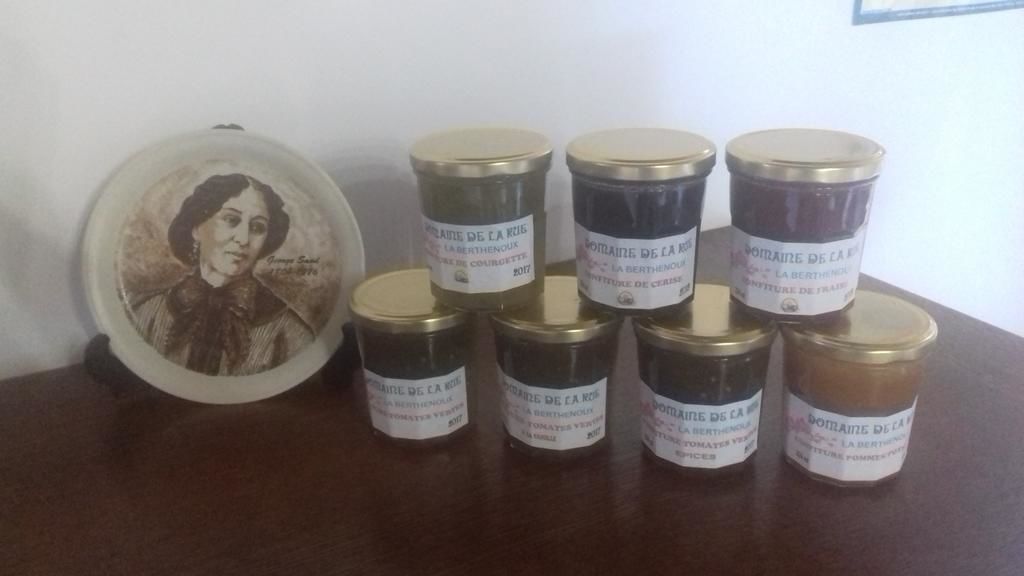 A collection of jars with labels, a framed picture, and a wooden surface.