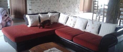A living room with a sectional sofa, a wooden coffee table, and a stone wall.