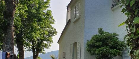 A courtyard with stone flooring, outdoor furniture, and a white building with shutters.
