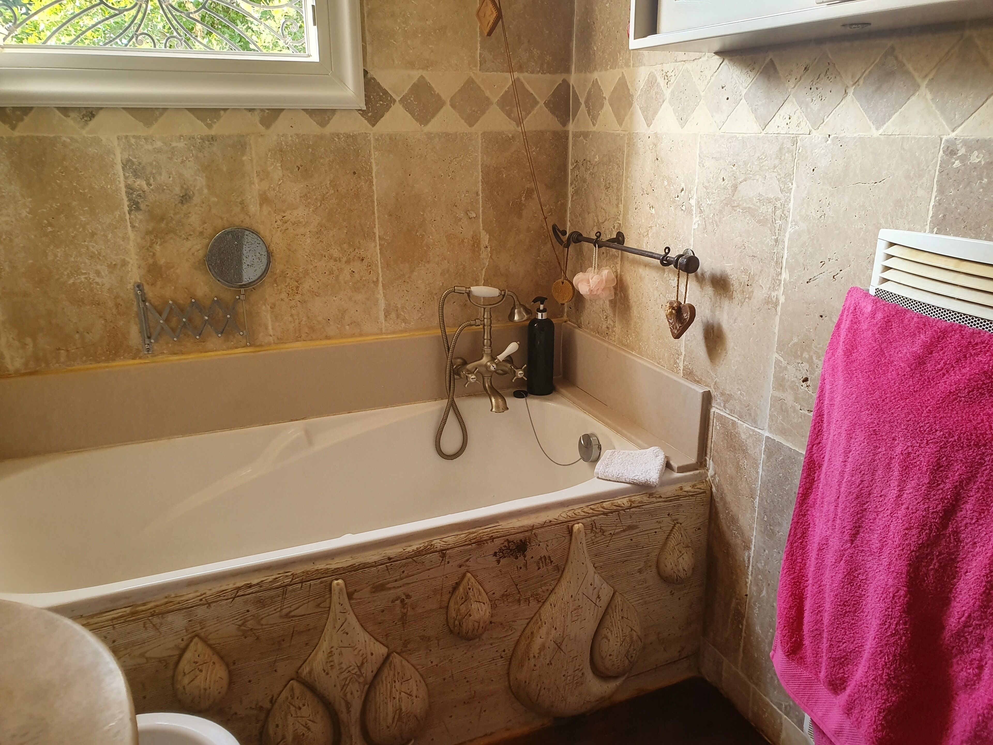 Une salle de bain avec une baignoire, une fenêtre et une serviette rose.