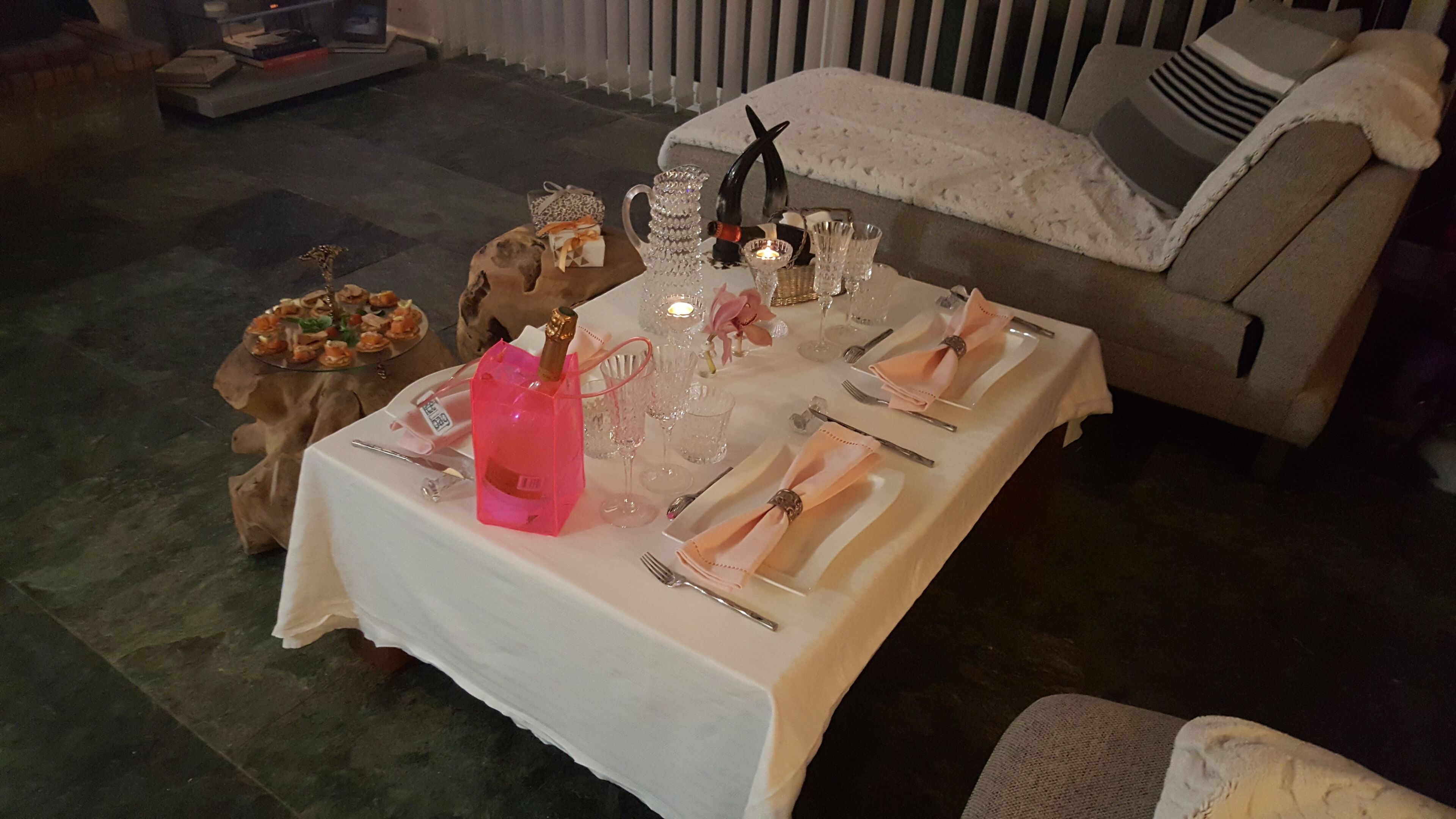 A dining table set for a meal with a white tablecloth, silverware, and glassware.