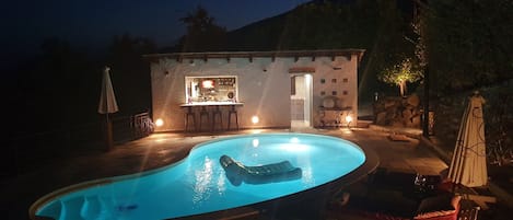 A swimming pool with a bar area and outdoor seating.