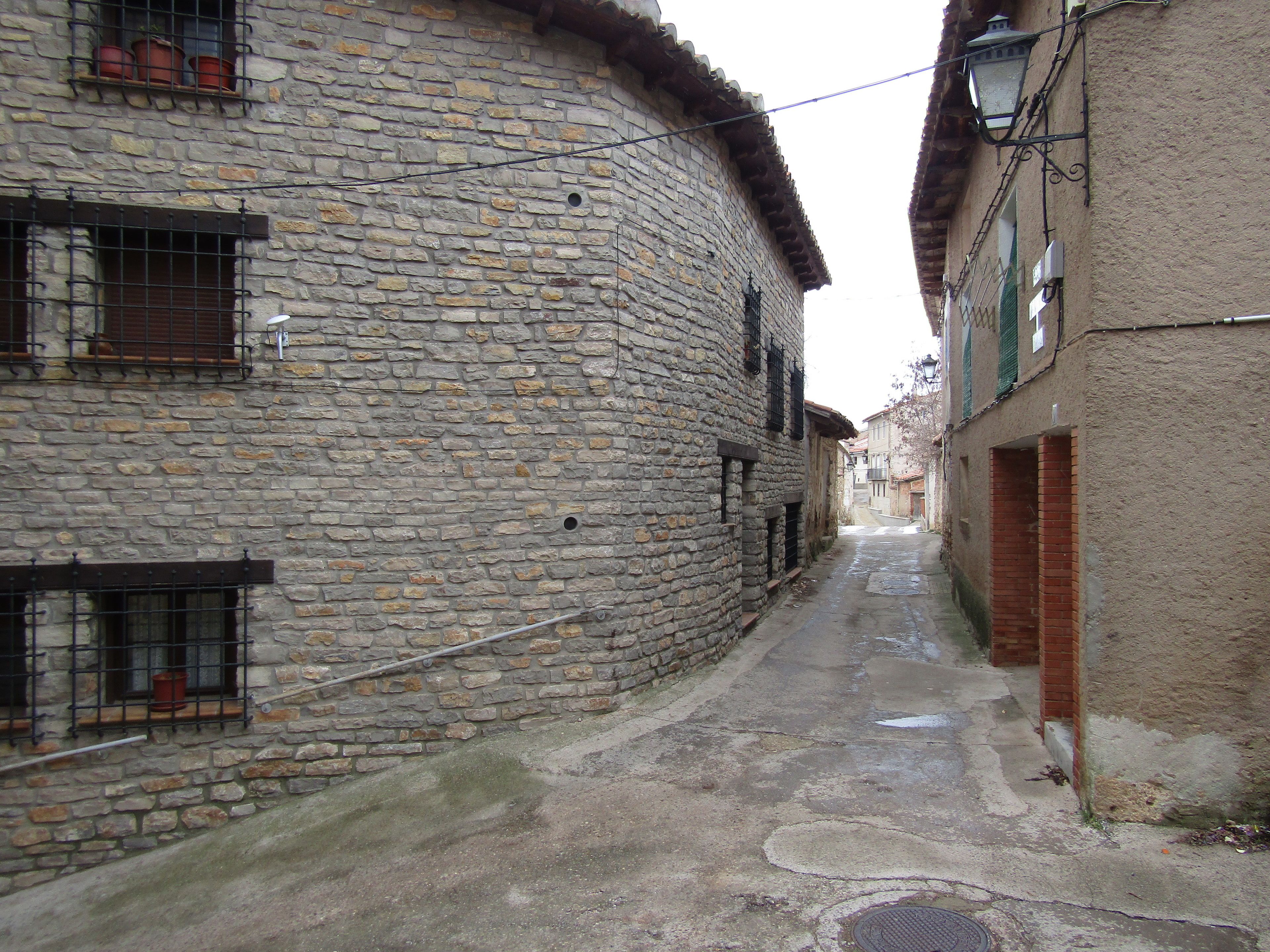 Una estrecha calle empedrada bordeada por edificios de piedra con ventanas y puertas visibles.