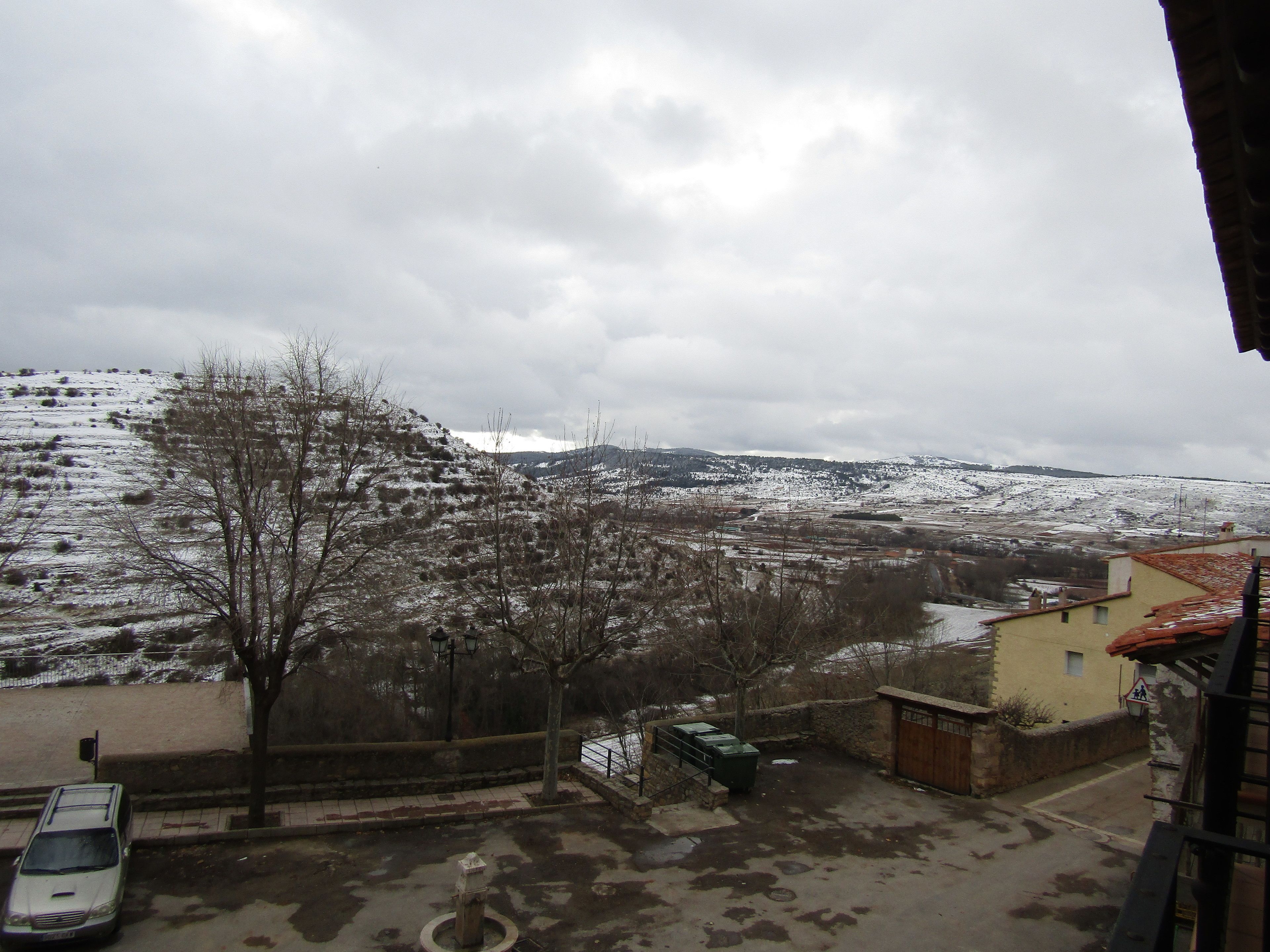 A view of a snow-covered landscape with a building in the foreground.