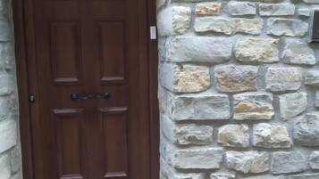 A wooden door with a stone wall and a sign indicating 'Habitaciones Hostal Paquita'.