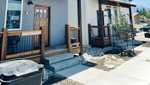 Ein modernes, zweistöckiges Haus mit Veranda, einer Holztür und einem Schild, das Parallelparken anzeigt.