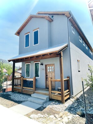 A two-story house with a covered porch, a front door, and a mailbox.