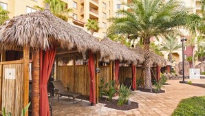 A resort with thatched-roof huts, palm trees, and lounge chairs. - 3BD/Orlando Near Disney - 5 Pools, Game Room, Café and Restaurant On-Site! (Lake Buena Vista)