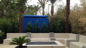 A modern outdoor seating area with a rectangular fire pit, surrounded by stone steps and palm trees. - 3BD/Vegas - Full Kitchen, Washer/Dryer, and Private Living Room! (Las Vegas)