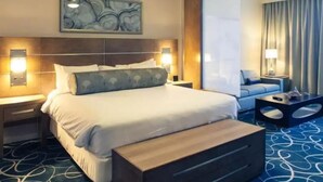 A hotel room with a large bed, a nightstand, a bedside table, a sofa, a coffee table, and a wall-mounted artwork. - Vegas Studio - Pools, Hot Tubs, and Shuttle to the Strip! (Las Vegas)