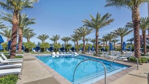 A pool area with lounge chairs and palm trees. - Vegas Studio - Pools, Hot Tubs, and Shuttle to the Strip! (Las Vegas)