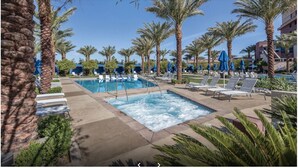 A pool area with lounge chairs and palm trees. - 1BD/Vegas - Pool, Hot Tub, and Shuttle to the Strip! (Las Vegas)