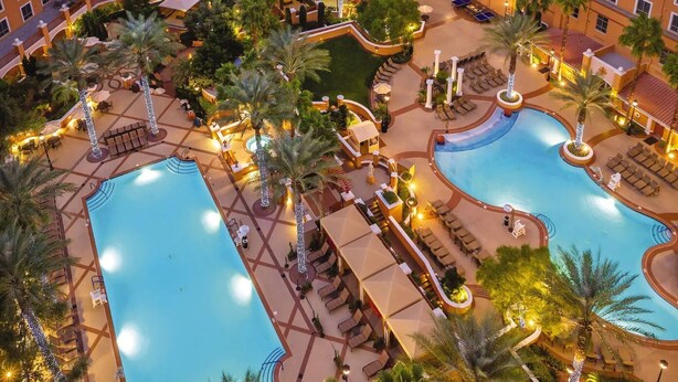 Un resort con varias piscinas, palmeras y zonas de estar al aire libre.