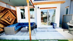A modern outdoor living area with a blue sofa set, a wicker coffee table, and a barbecue grill. - Downtown BV Retreat _311_ Steps to Main & River (Buena Vista)
