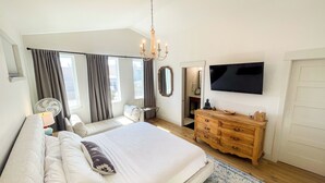 A bedroom with a large bed, a wooden dresser, a television, and a window with curtains. - Downtown BV Retreat _311_ Steps to Main & River (Buena Vista)