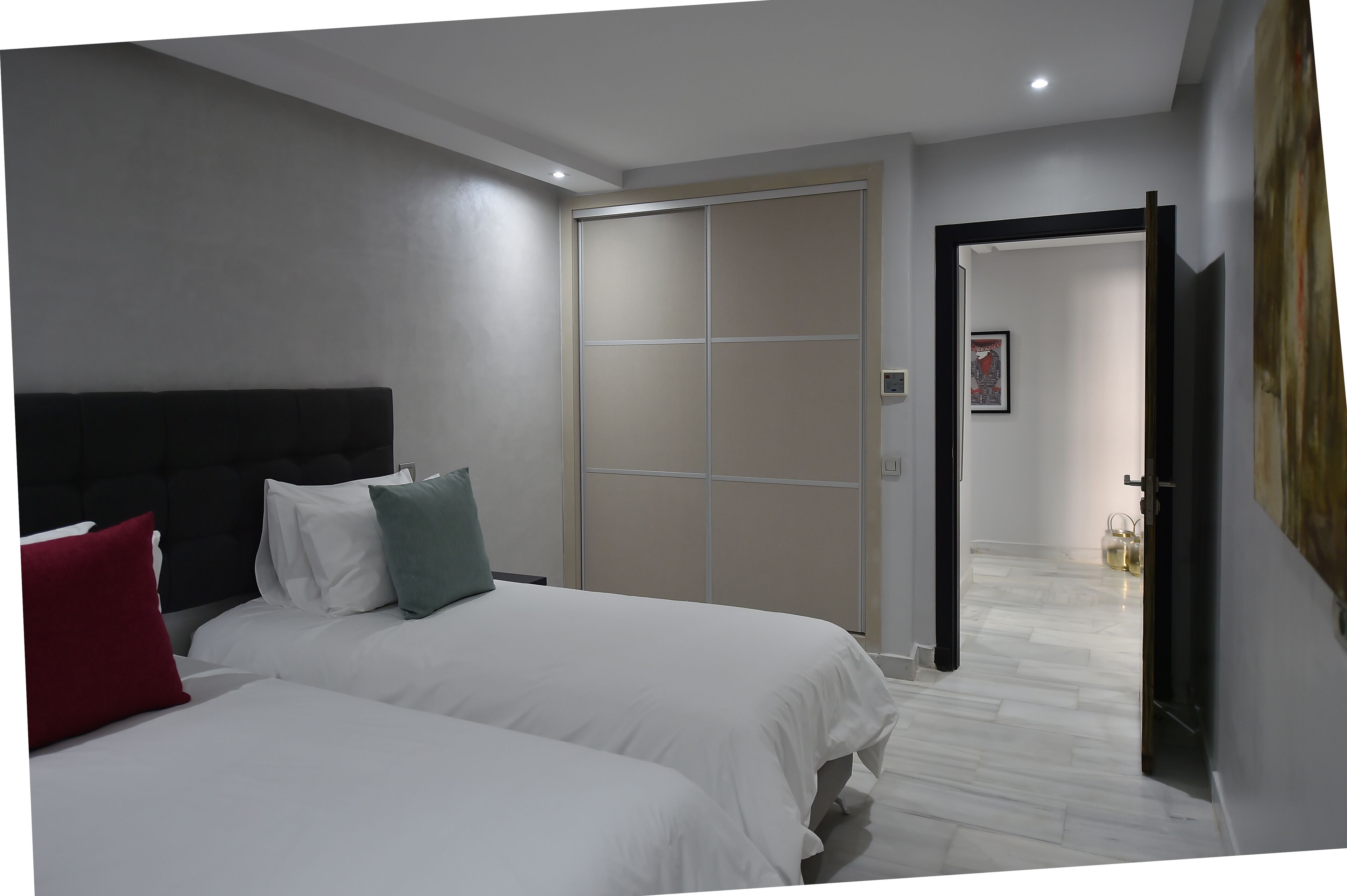 A bedroom with two beds, a sliding door closet, and a hallway leading to another room.