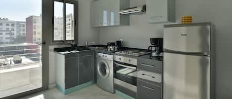 Una cocina moderna con lavadora, horno y refrigerador integrados. Cuenta con un ventanal y vistas a la ciudad.