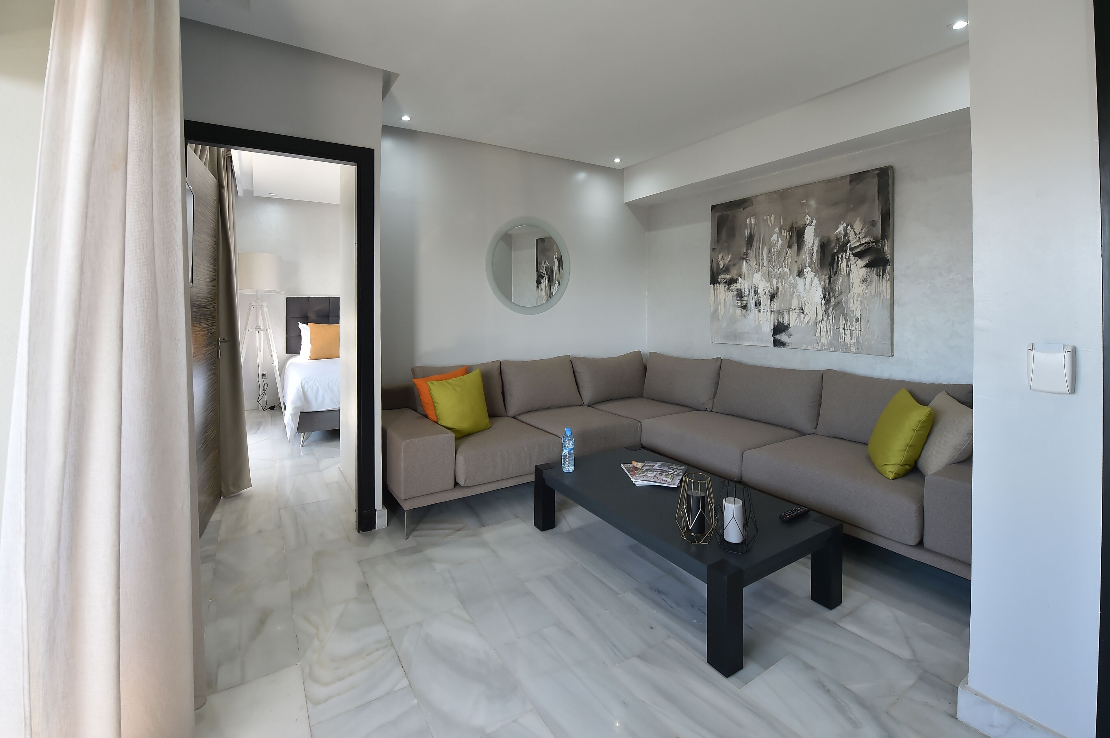 A modern living room with a beige sofa, a black coffee table, and a large abstract painting on the wall.