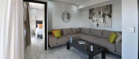 A modern living room with a beige sofa, a black coffee table, and a large abstract painting on the wall.