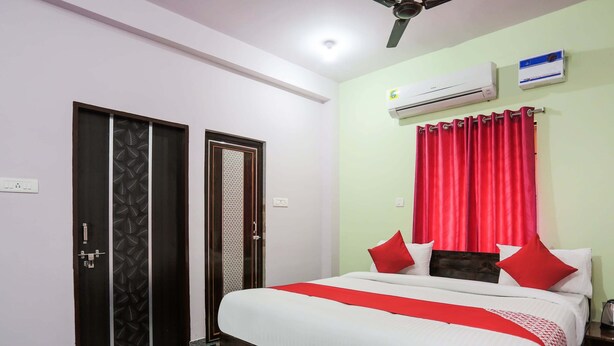 A hotel room with a bed, red curtains, an air conditioner, and a ceiling fan. - Oyo 43512 Bijaya Palace (Bhubaneshwar)