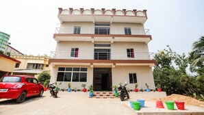 A multi-story building with a balcony on the second floor, a gated entrance, and several potted plants around the entrance. - Oyo 43512 Bijaya Palace (Bhubaneshwar)