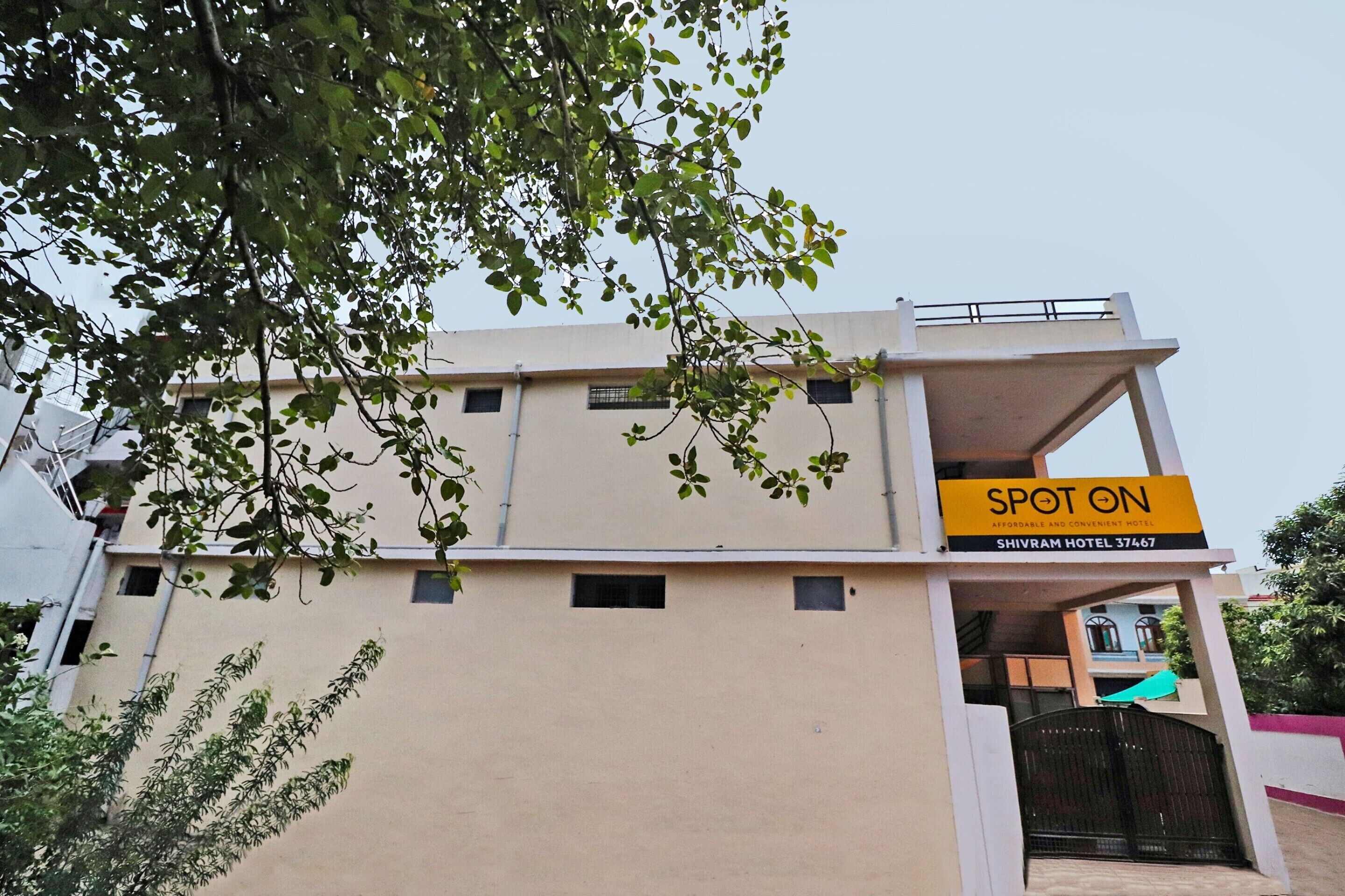 A hotel named "SPOT ON" with a signboard, a flat facade, and a gated entrance.
