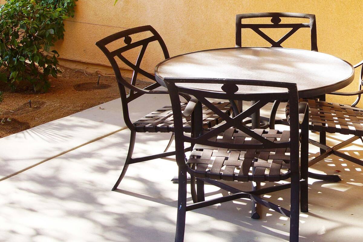 A round table with four chairs, a concrete floor, and a yellow wall.