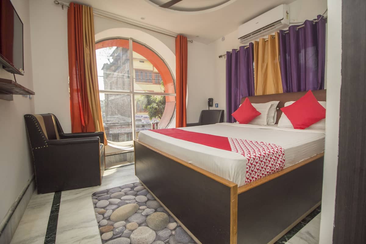 A bedroom with a bed, a chair, a desk, and a window with curtains.