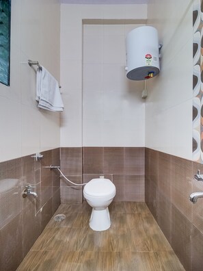 A bathroom with a toilet, a towel rack, a shower, and a water heater. - OYO 29022 Golden Imperial (Greater Noida)