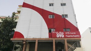 A building with a red and white facade, featuring a large curved red section and a smaller white section. - OYO Flagship 16390 Chukkapalli Chambers (Vijayawada)