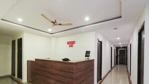A reception desk with a ceiling fan, a sign with icons, and a corridor with doors. - OYO Flagship 16390 Chukkapalli Chambers (Vijayawada)
