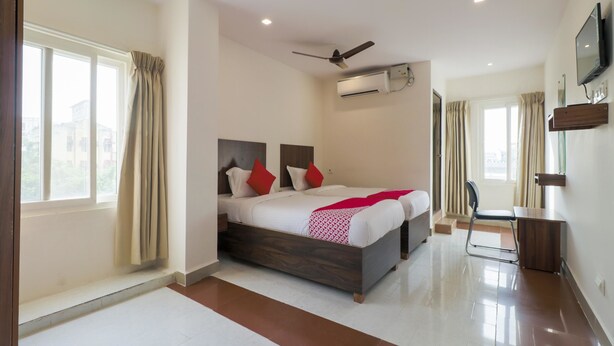A modern hotel room with a large bed, a desk, and a TV. - OYO Flagship 16390 Chukkapalli Chambers (Vijayawada)