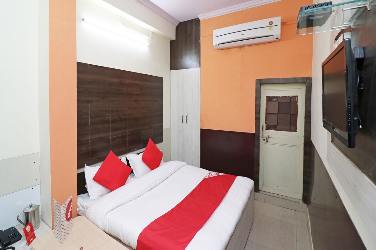 A hotel room with a bed, a wardrobe, a television, and an air conditioning unit.