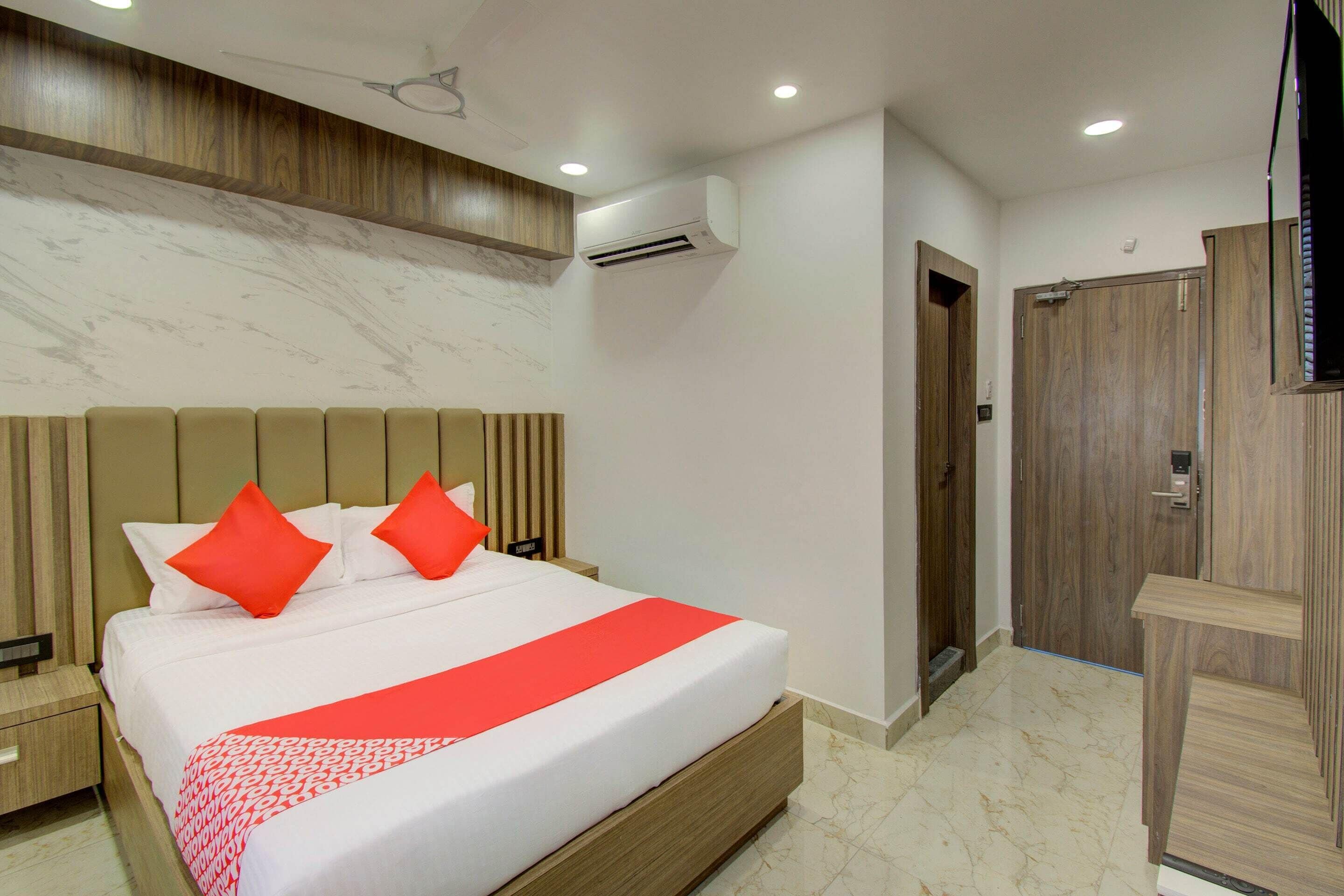 Een hotelkamer met een groot bed, een houten hoofdbord en een rood kussen.