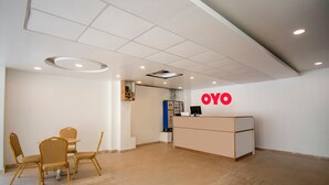 A reception area with a reception desk, a seating area with chairs, and a tiled floor. - Capital O 23031 V Hotel (Penumuluru)