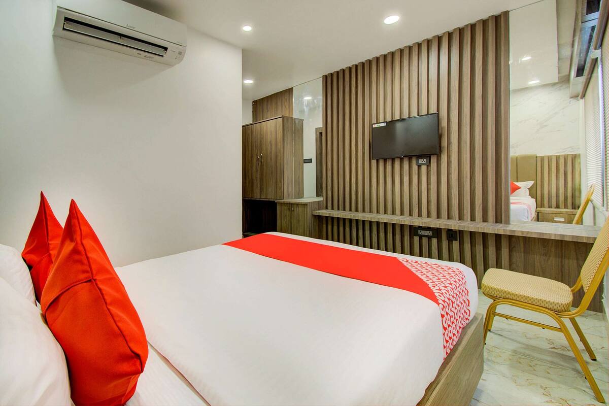 Een hotelkamer met een bed, een bureau, een stoel, een televisie en een spiegel.