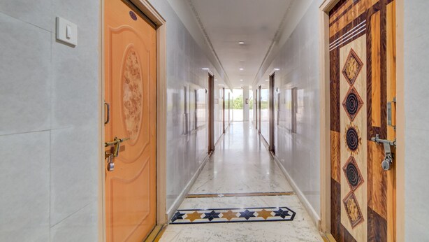 A long, well-lit hallway with marble flooring, a patterned carpet, and two ornate doors. - OYO 29087 Hotel Golden Pride (Hyderabad)