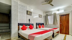 A hotel room with two beds, a wooden headboard, a marble floor, a ceiling fan, and a wooden door. - OYO 29087 Hotel Golden Pride (Hyderabad)